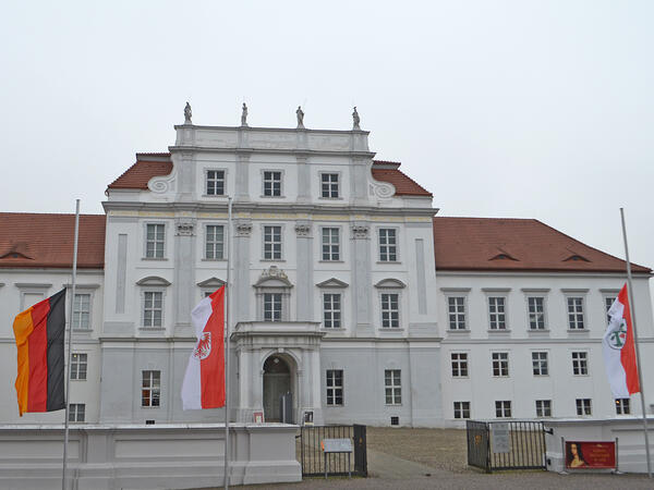 Vor dem Schloss Oranienburg wehen die Flaggen zum Gedenken an die Opfer auf Halbmast.