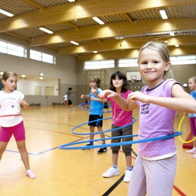 Kinder trainieren mit dem Hula-Hoop-Reifen in der Sporthalle in Germendorf.